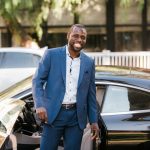 man in blue suit standing beside black car