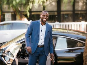 man in blue suit standing beside black car