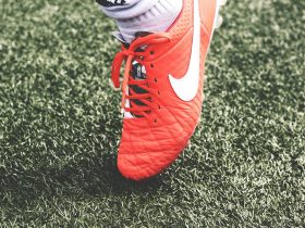 unpaired orange and white Nike soccer cleat