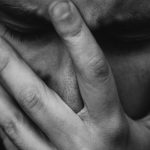 grayscale photo of person placing hand on face