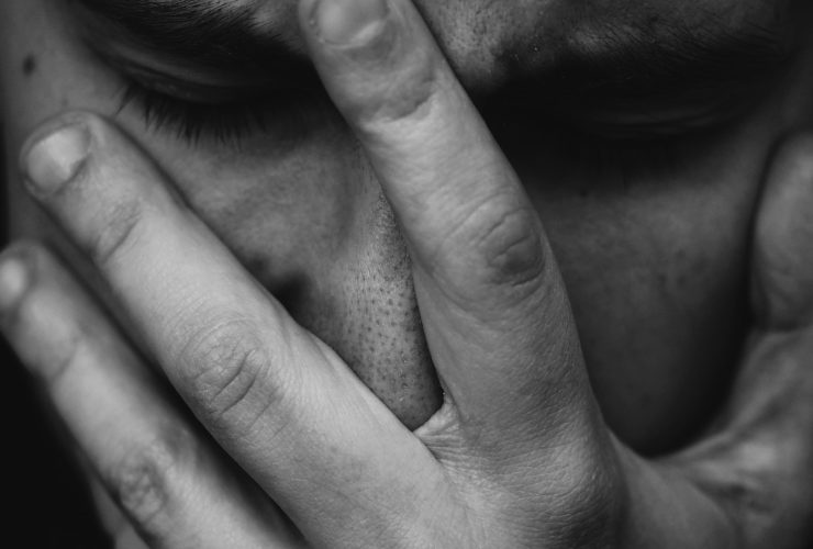 grayscale photo of person placing hand on face