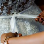 person holding white ribbon on white and gray floral textile