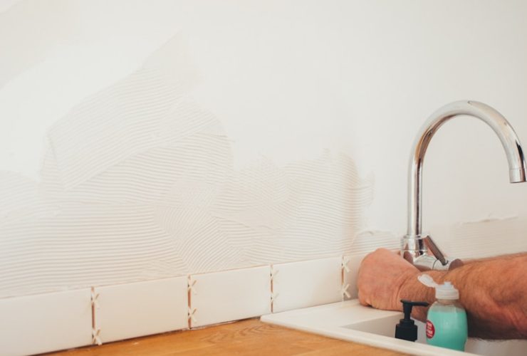 person holding gray curved faucet