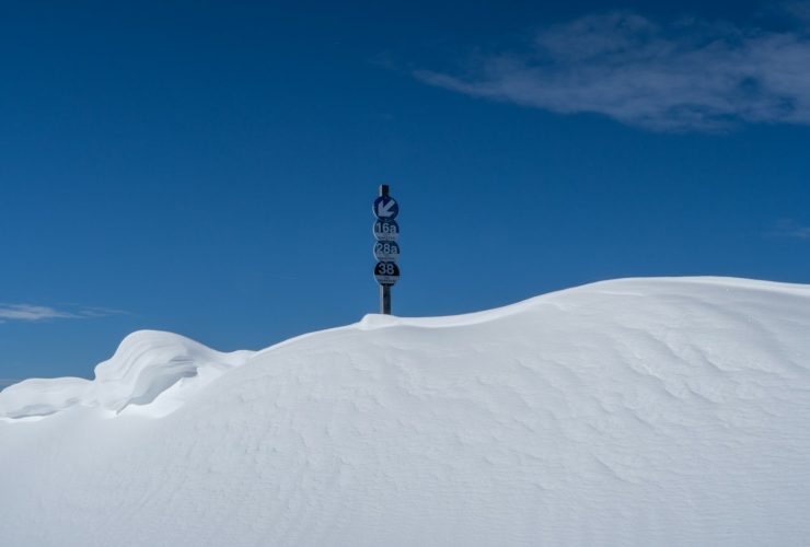 a street sign sitting on top of a snow covered hill